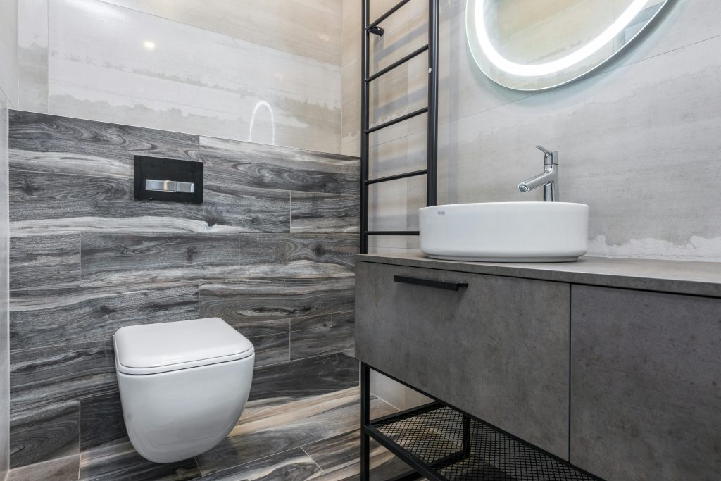 A sleek modern bathroom featuring gray tiles, a stylish sink, and a minimalist design.